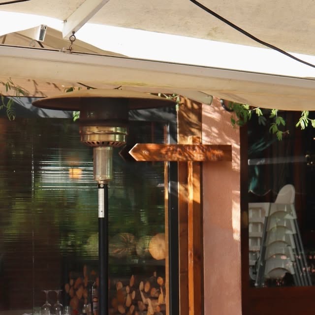 Terrassa del Restaurant La Torreta amb tendal, estufa exterior i llenya apilada