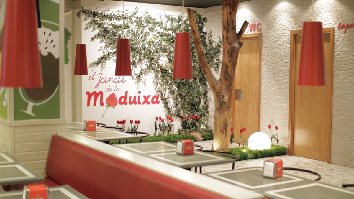 Interior del Restaurant La Maduixa amb el mural «El Jardí de la Maduixa», llums còniques vermelles i parament vegetal