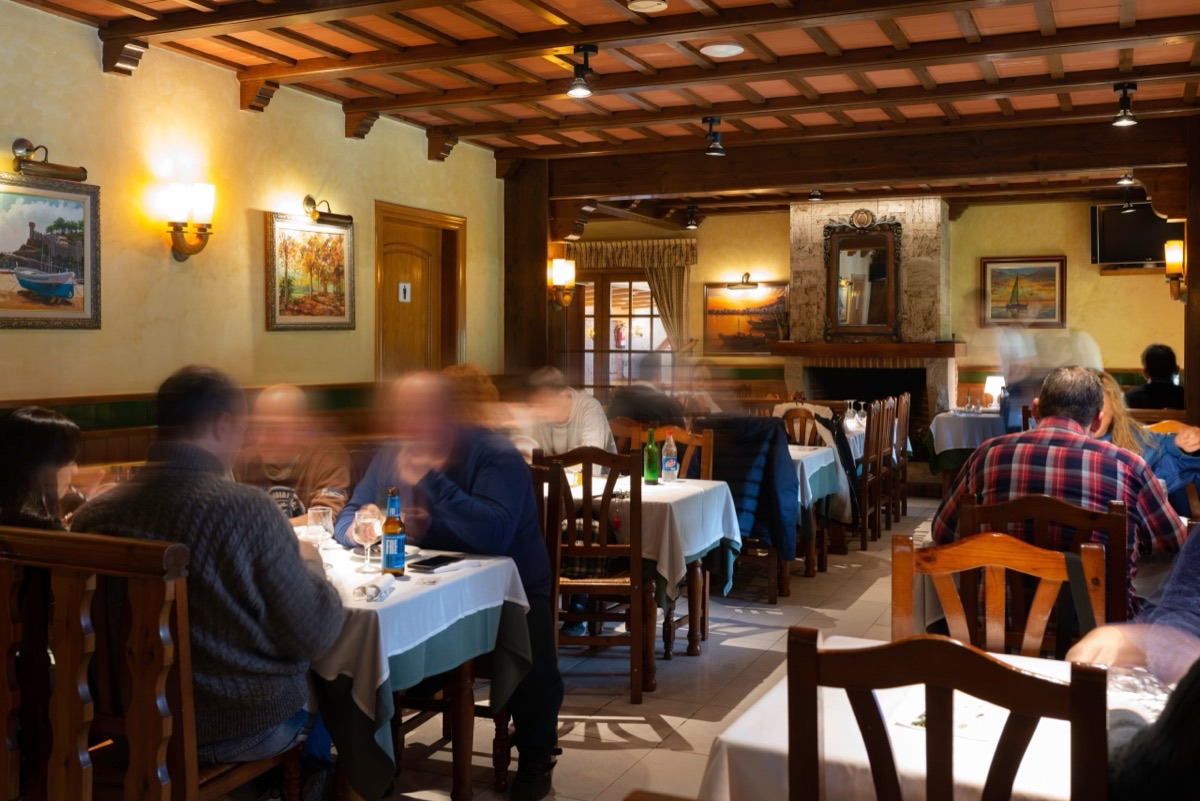 Menjador del Restaurant La Torreta amb sostre de bigues de fusta, taules parades amb estovalles blanques i clients dinant