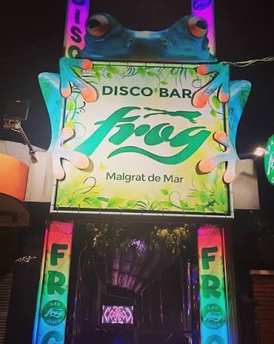 Façana il·luminada del disco bar The FROG a Malgrat de Mar, amb el rètol en forma de granota